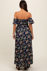 woman wearing a navy blue off-shoulder floral maternity maxi dress with wide sleeves and a fitted waist, showing her baby bump
