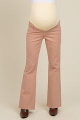 woman wearing pink maternity flared jeans with a beige belly support band and brown heeled boots
