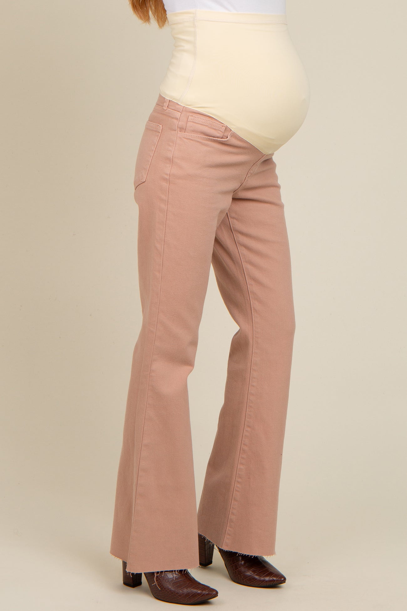 woman wearing light pink flared maternity jeans with a support panel and visible baby bump