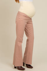 woman wearing light pink flared maternity jeans with a support panel and visible baby bump