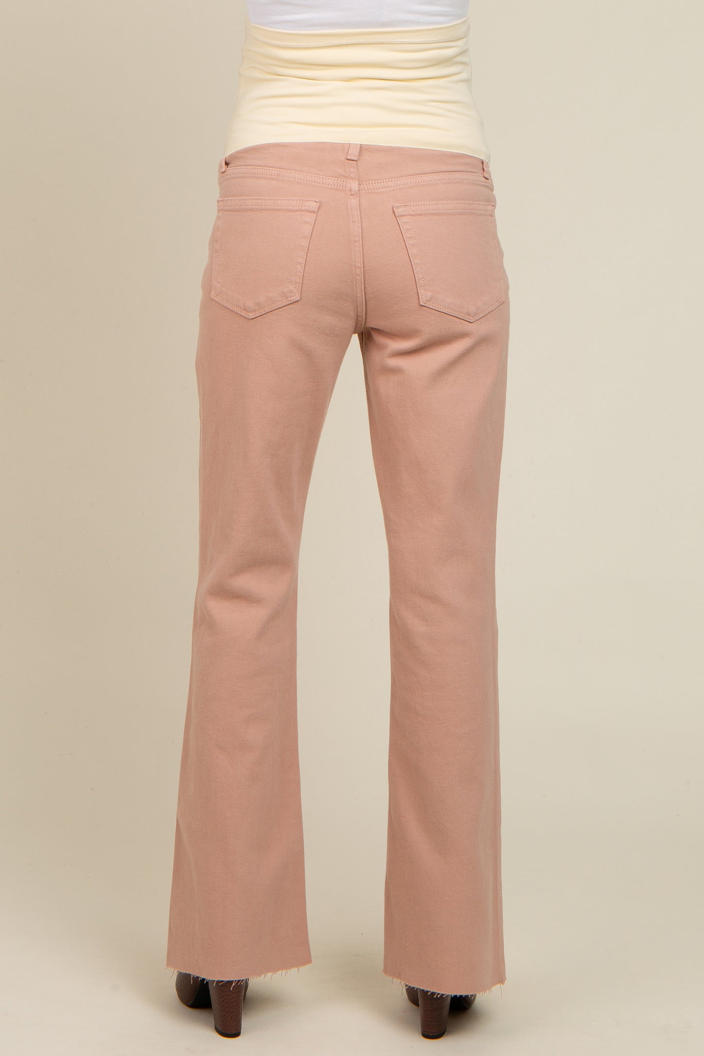 woman wearing light pink maternity flared jeans, viewed from the back, showing the waistband and pockets