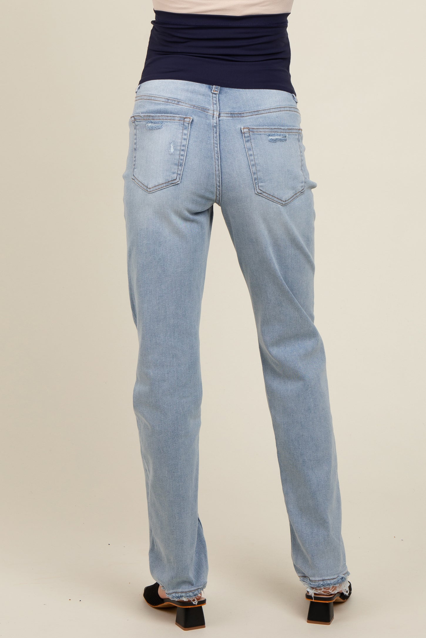 woman wearing light blue maternity jeans with a fitted waistband, viewed from the back