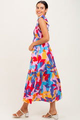 woman wearing a colorful floral maxi dress with ruffled sleeves and tiered skirt, smiling and posed sideways