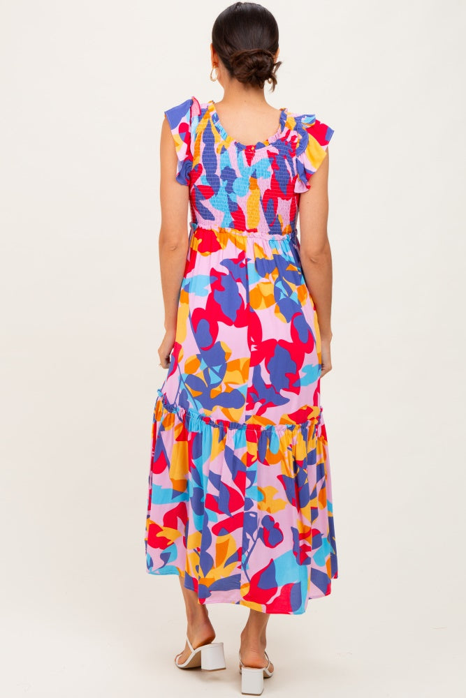 woman wearing a colorful floral maxi dress with ruffled sleeves and a tiered skirt, viewed from the back