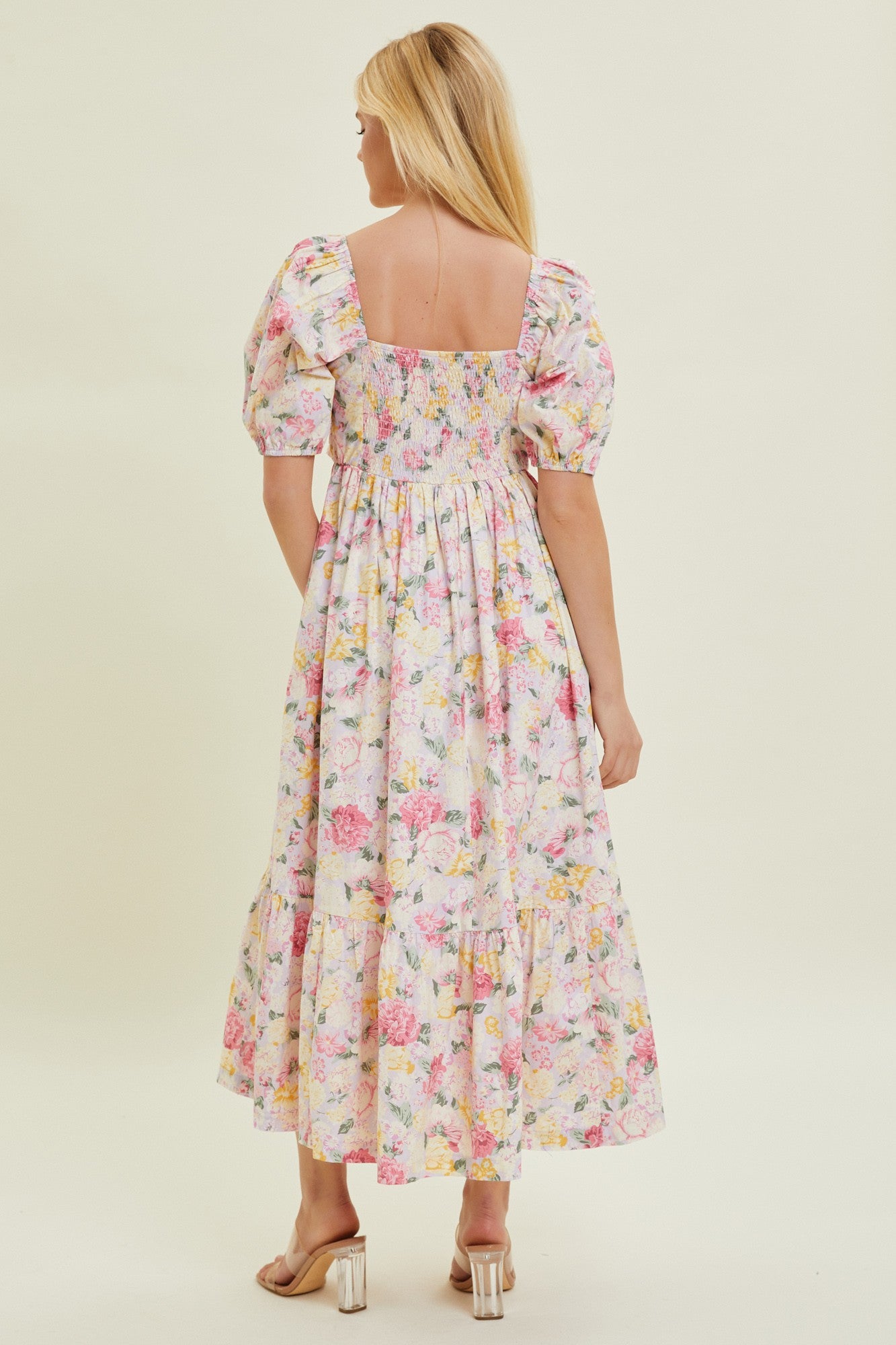 woman wearing a long floral maxi dress with puff sleeves and a tiered skirt, showing the back view
