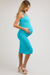 woman wearing a turquoise knitted midi maternity dress and holding her baby bump