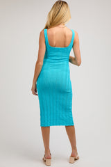 woman wearing a turquoise maternity dress with a ribbed texture and fitted silhouette, showcasing a back view