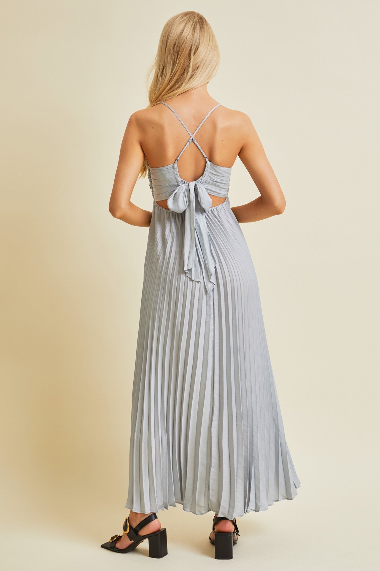 woman wearing a light blue pleated maxi dress with a back bow detail and spaghetti straps
