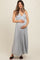 woman wearing a light gray pleated maternity maxi dress and holding her baby bump