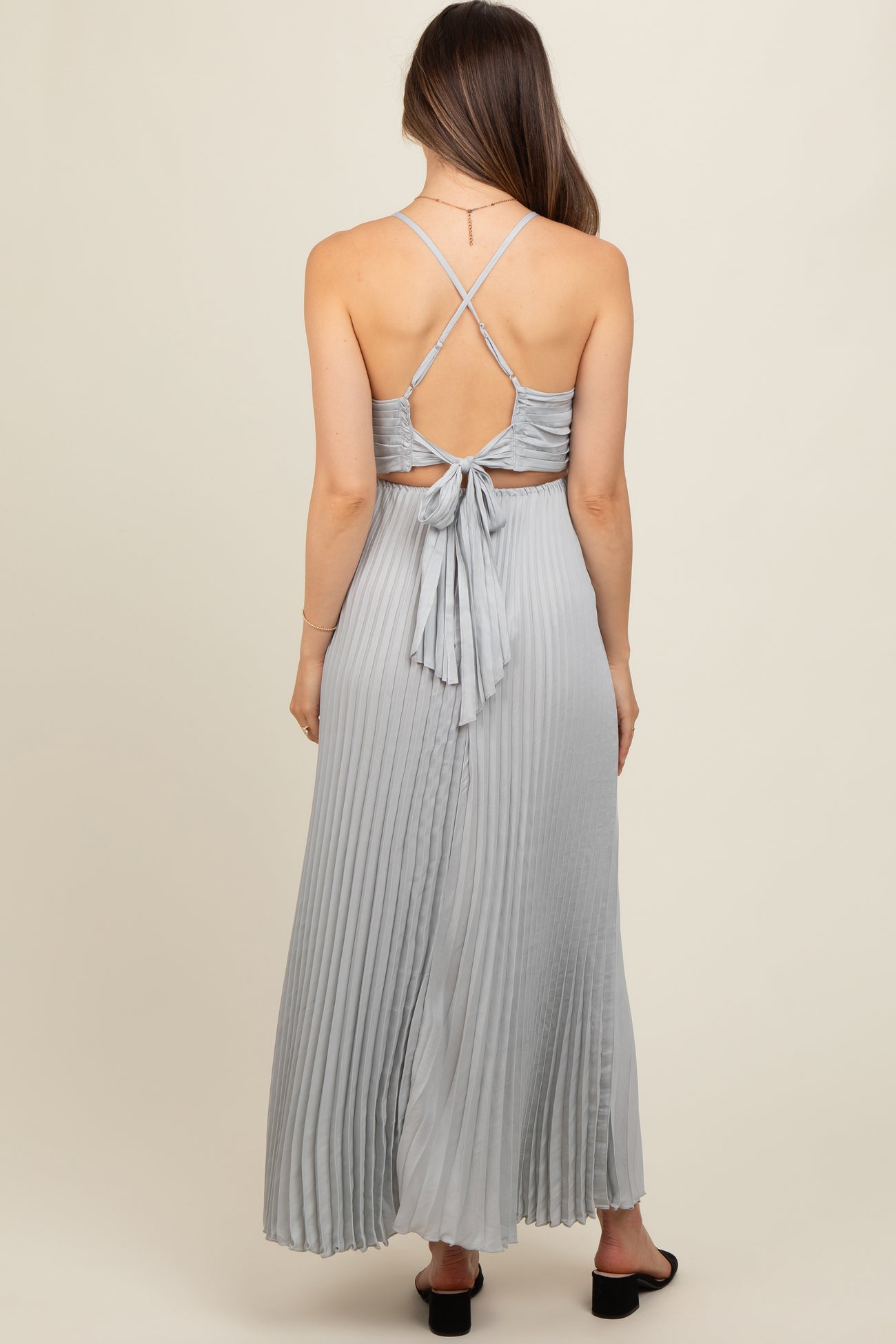 woman wearing a light grey maternity maxi dress with a pleated design and a tied back detail
