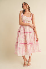 woman wearing a floral tiered midi dress with pink accents and tie shoulder straps