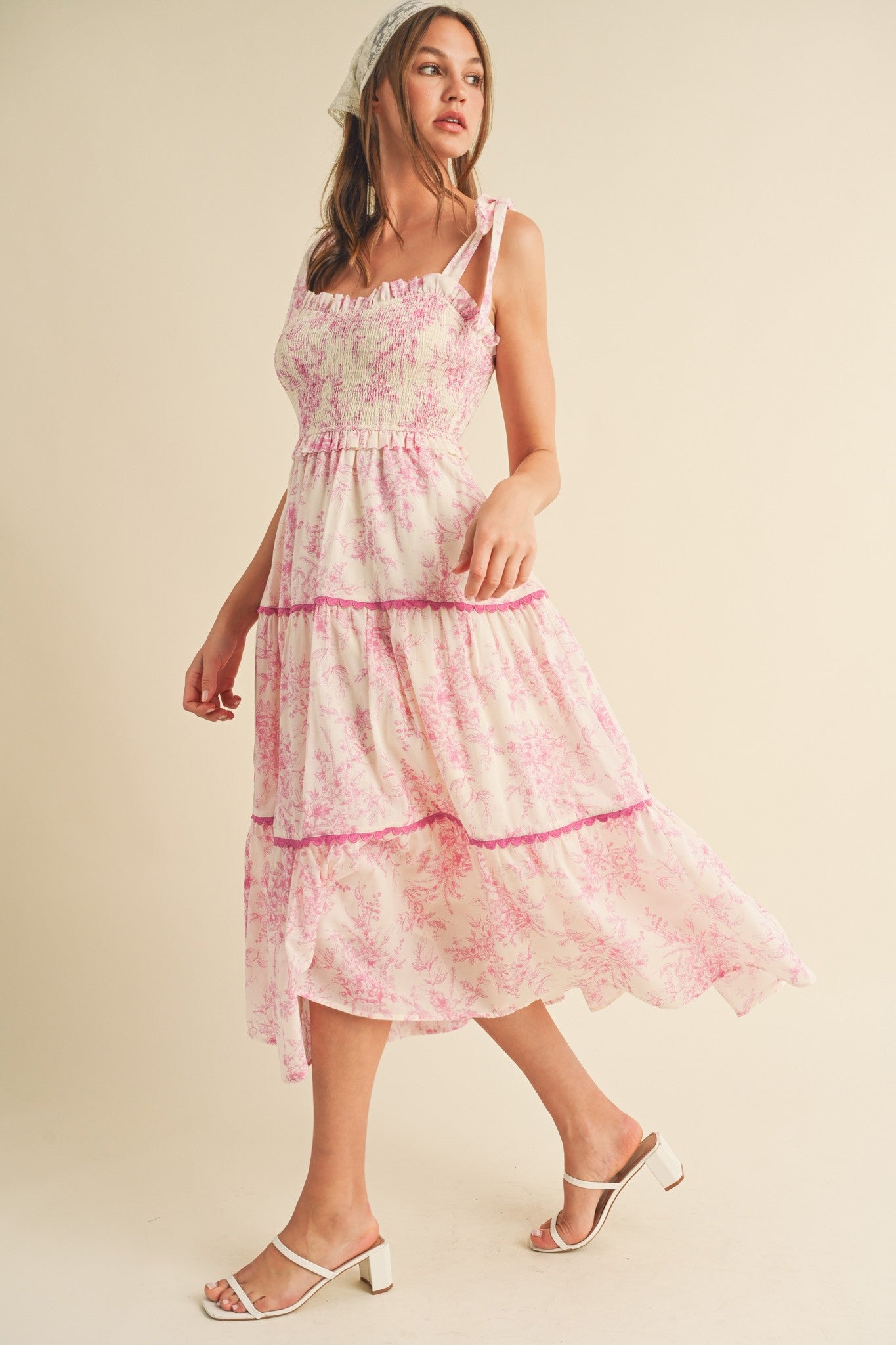 woman wearing a sleeveless pink and white floral tiered maxi dress with ruffled details and a headscarf
