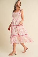 woman wearing a sleeveless pink and white floral tiered maxi dress with ruffled details and a headscarf