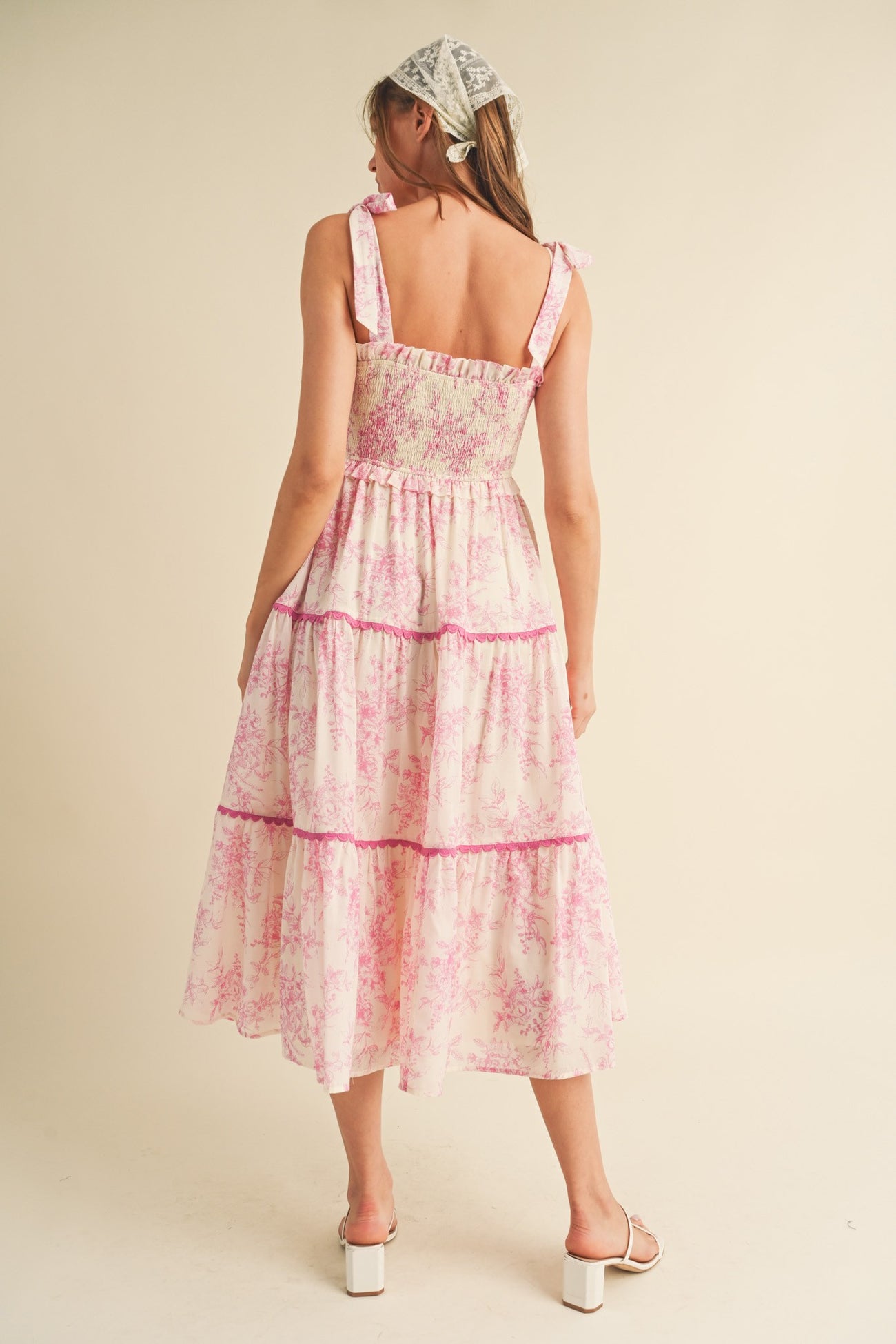 woman wearing a pink floral tiered maxi dress with ruffled straps, viewed from the back
