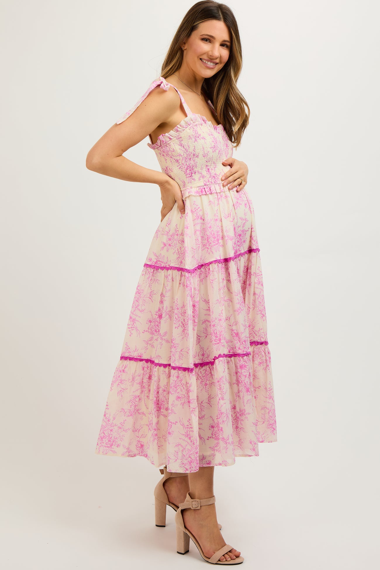 woman wearing a pink floral maternity maxi dress with ruffles and a visible baby bump