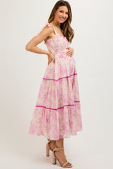 woman wearing a pink floral maternity maxi dress with ruffles and a visible baby bump