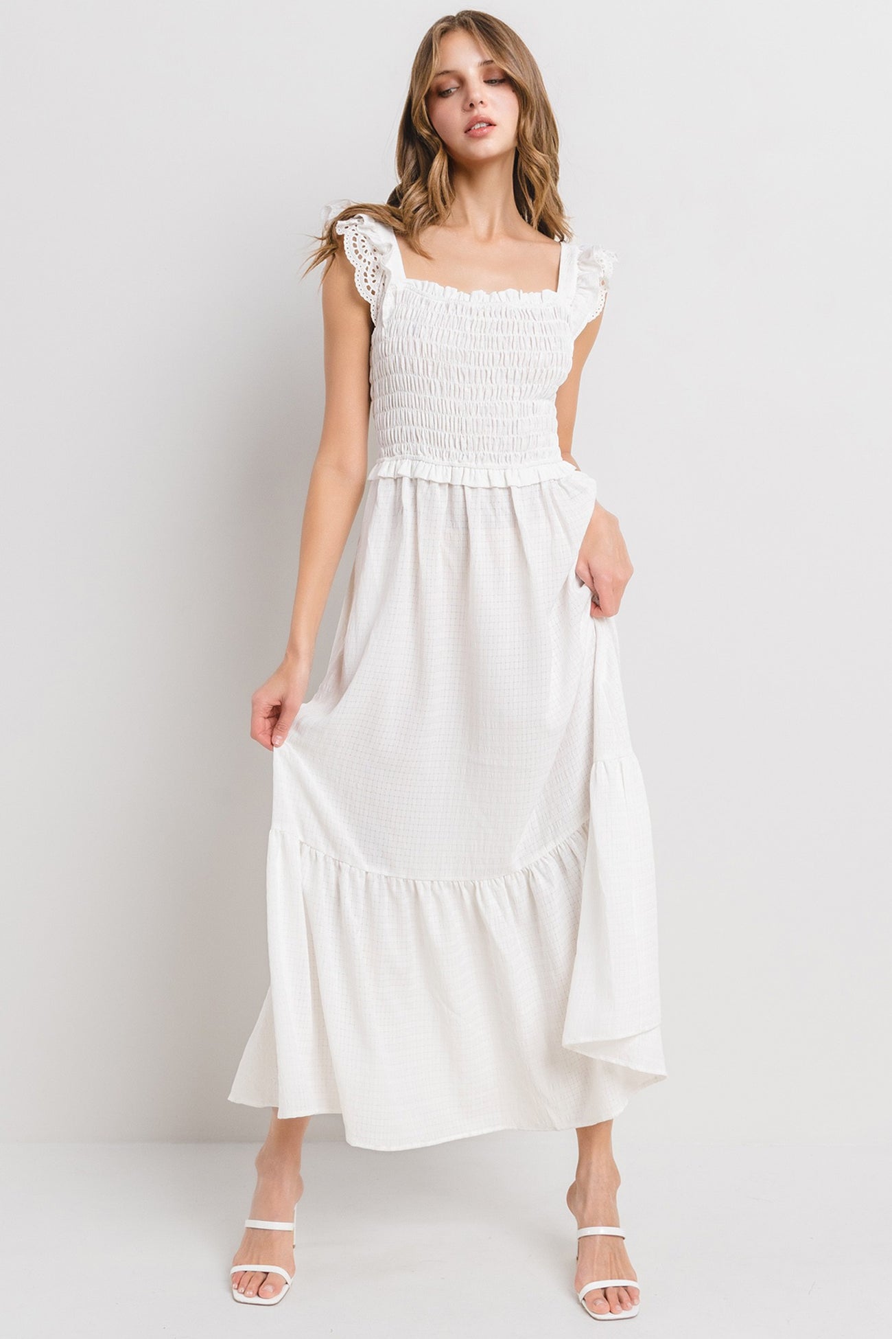woman wearing a white maxi dress with smocked bodice and lace trim straps