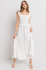 woman wearing a white maxi dress with smocked bodice and lace trim straps