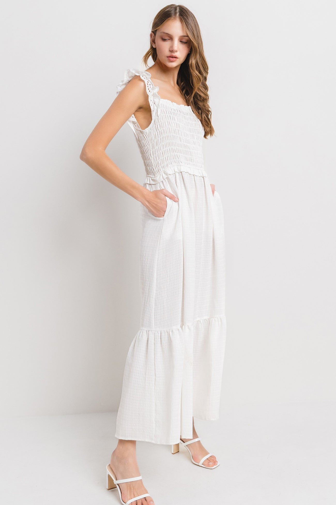woman wearing a white smocked maxi dress with ruffled sleeves and side pockets