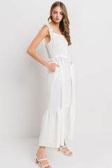 woman wearing a white smocked maxi dress with ruffled sleeves and side pockets