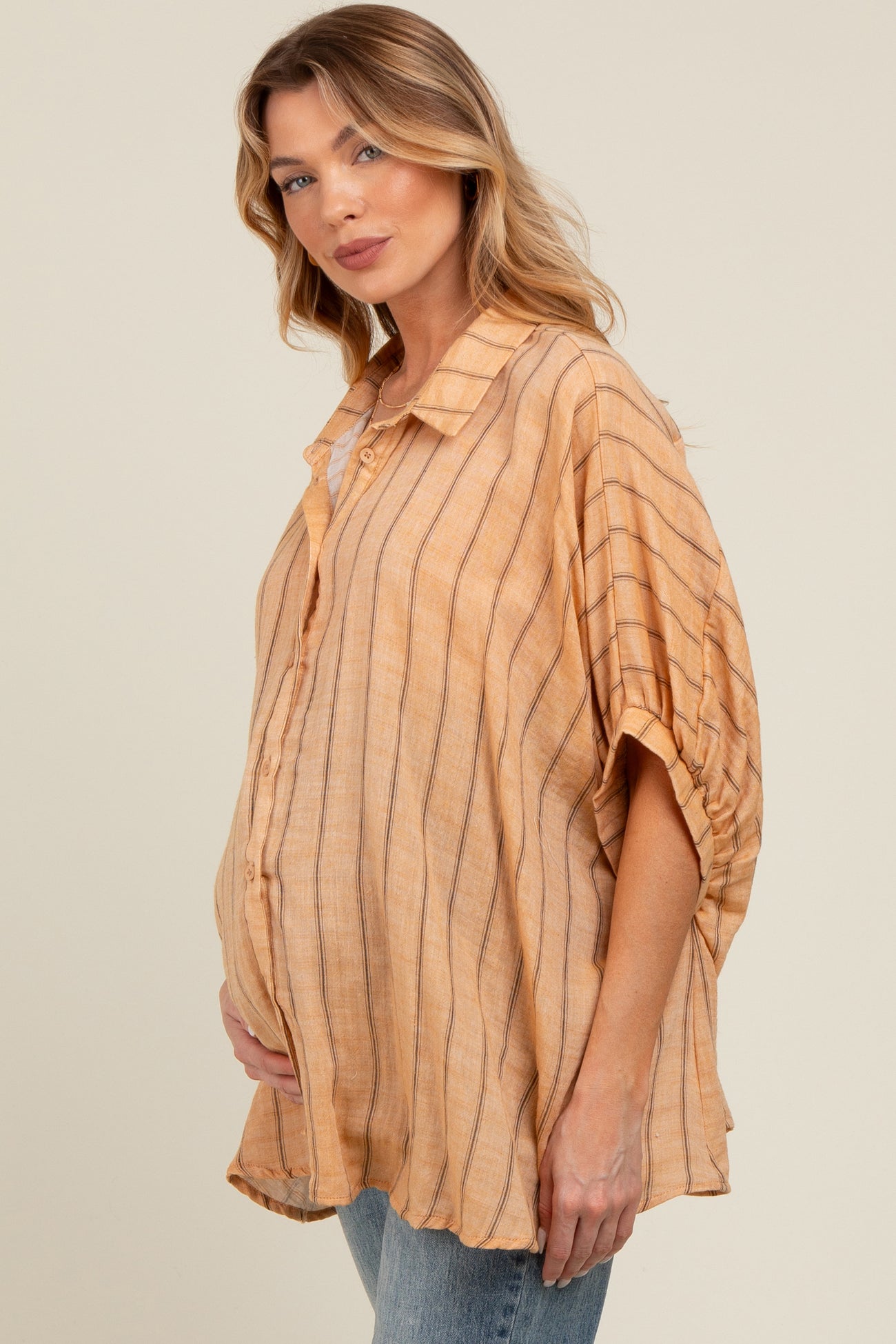 woman wearing a light orange striped maternity top with a loose fit and a visible baby bump