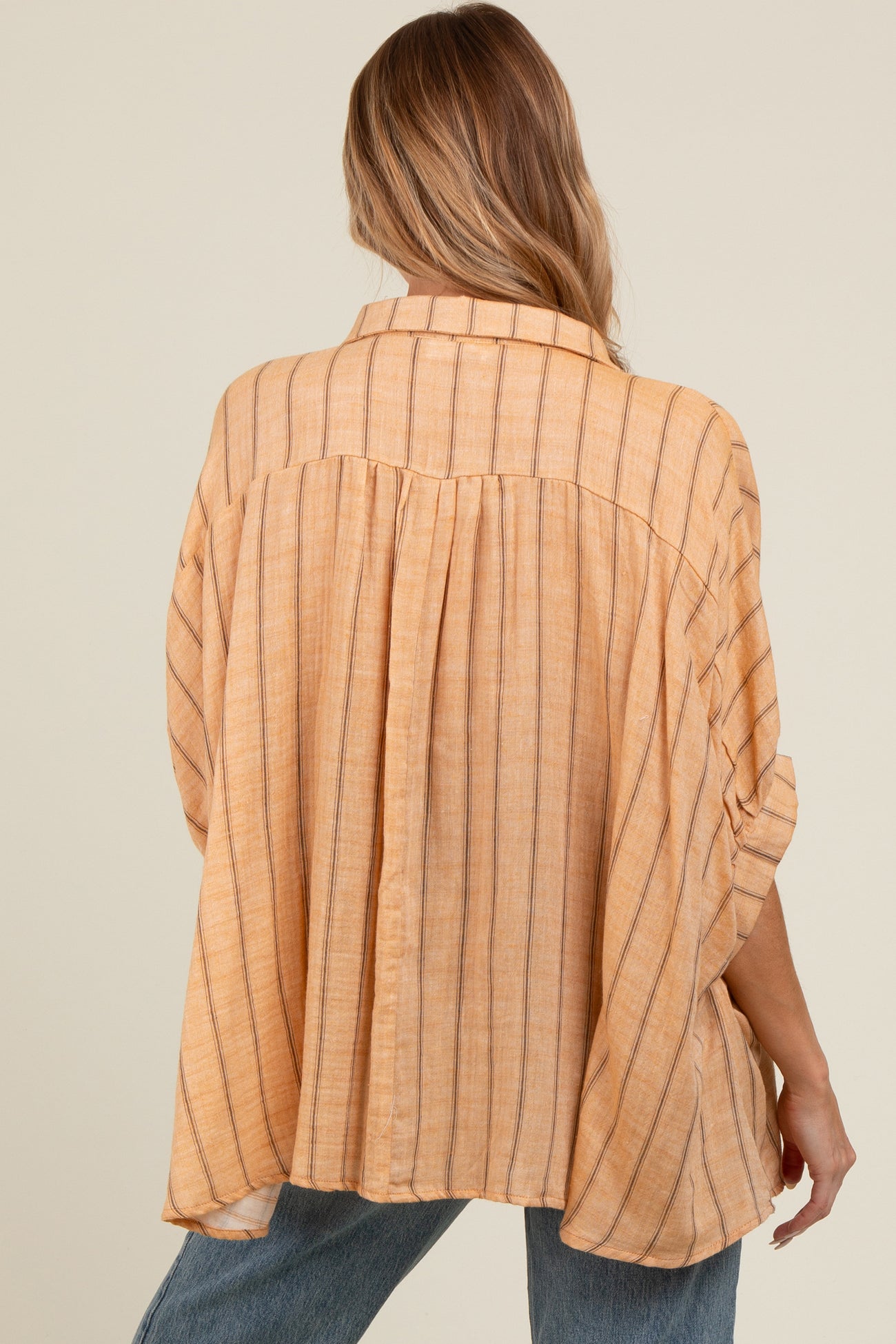 woman wearing a light orange striped maternity blouse with a relaxed fit and back pleat detail