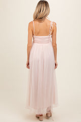 woman wearing a light pink maternity maxi dress with spaghetti straps and a smocked bodice, showing a flowing skirt