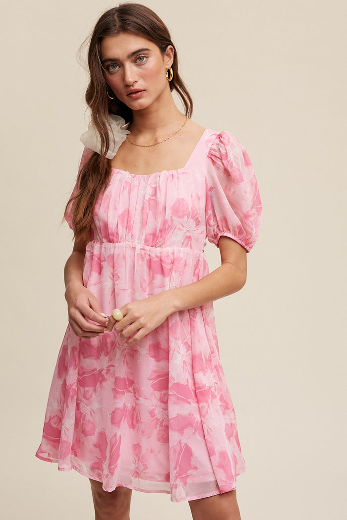 woman wearing a pink floral puff sleeve dress with a square neckline and gathered waist