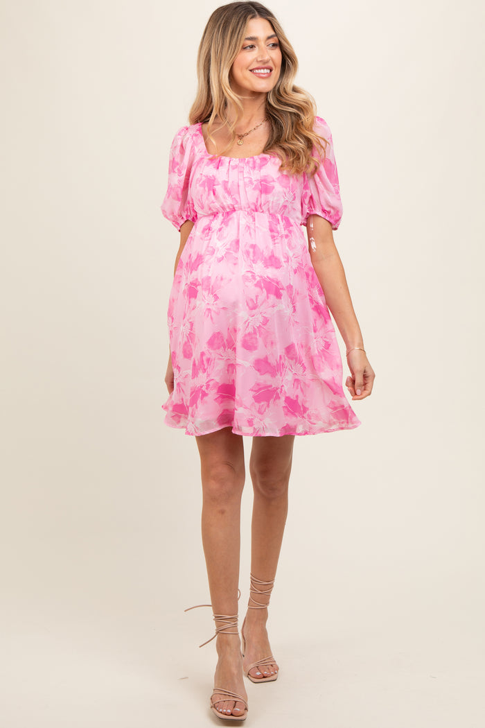 woman wearing a pink floral maternity dress with puff sleeves and a baby bump visible
