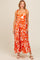 woman wearing a floral orange maxi dress with shoulder ties and a flared skirt