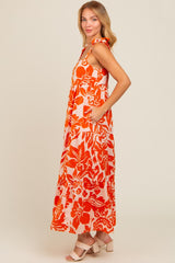 woman wearing a long floral maxi dress in orange and white with ruffled straps and pockets