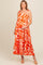 woman wearing a pink and orange floral maternity maxi dress with tied straps and a visible baby bump