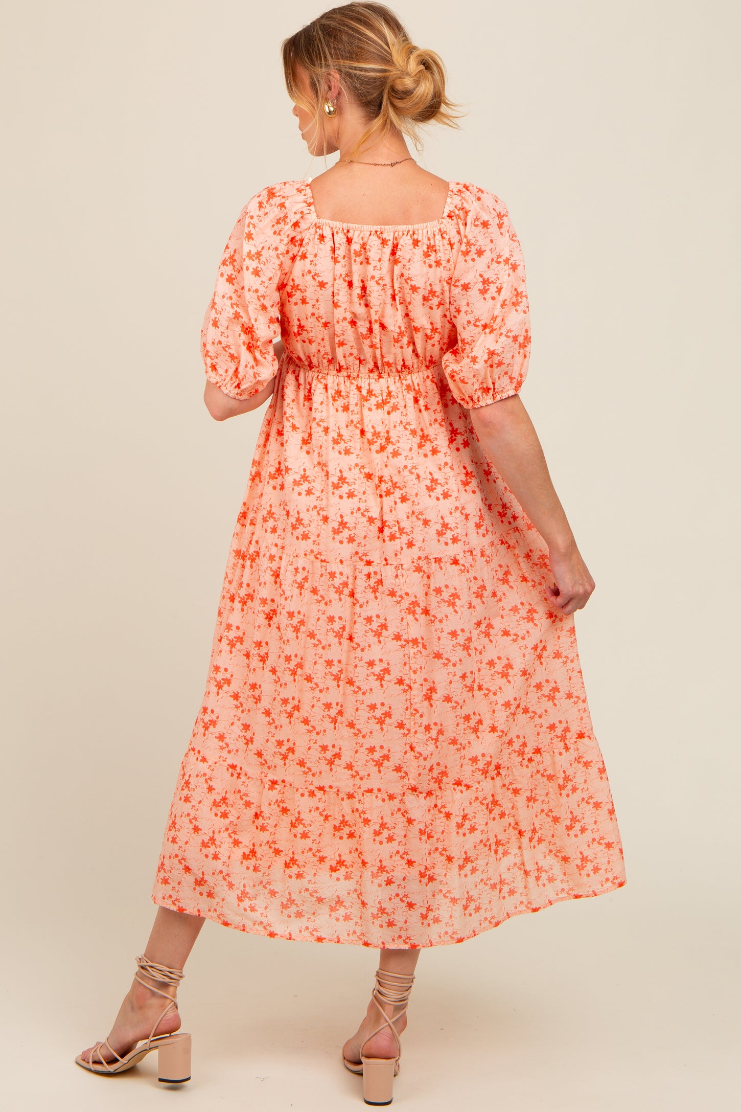 woman wearing a peach floral maternity dress with puff sleeves and a square back, showcasing a flowing silhouette