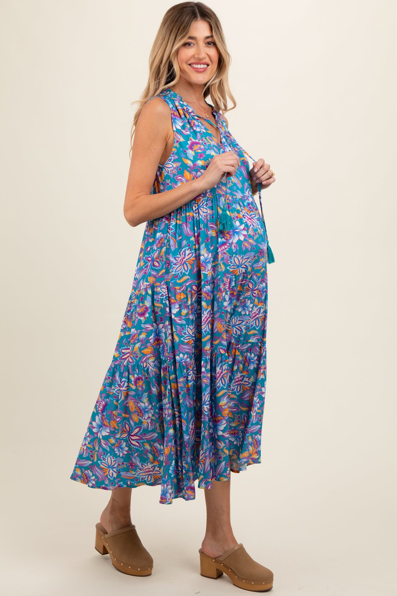 woman wearing a colorful floral sleeveless maternity dress with a flowing skirt and a visible baby bump