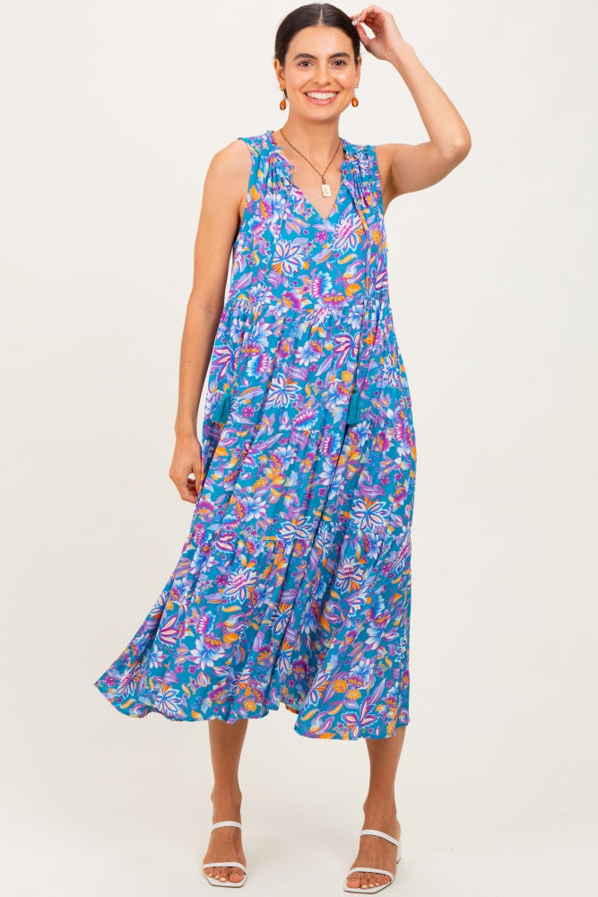 woman wearing a flowy floral sleeveless midi dress in vibrant blue with colorful patterns and relaxed fit