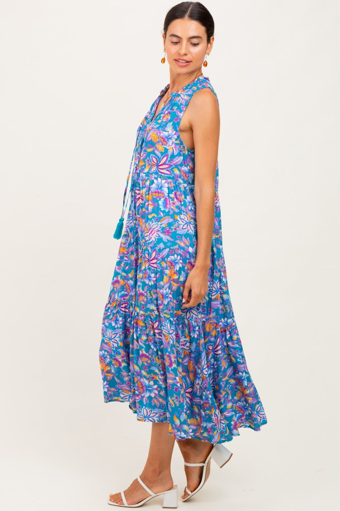 woman wearing a colorful floral maxi dress with a tiered skirt and tassel details