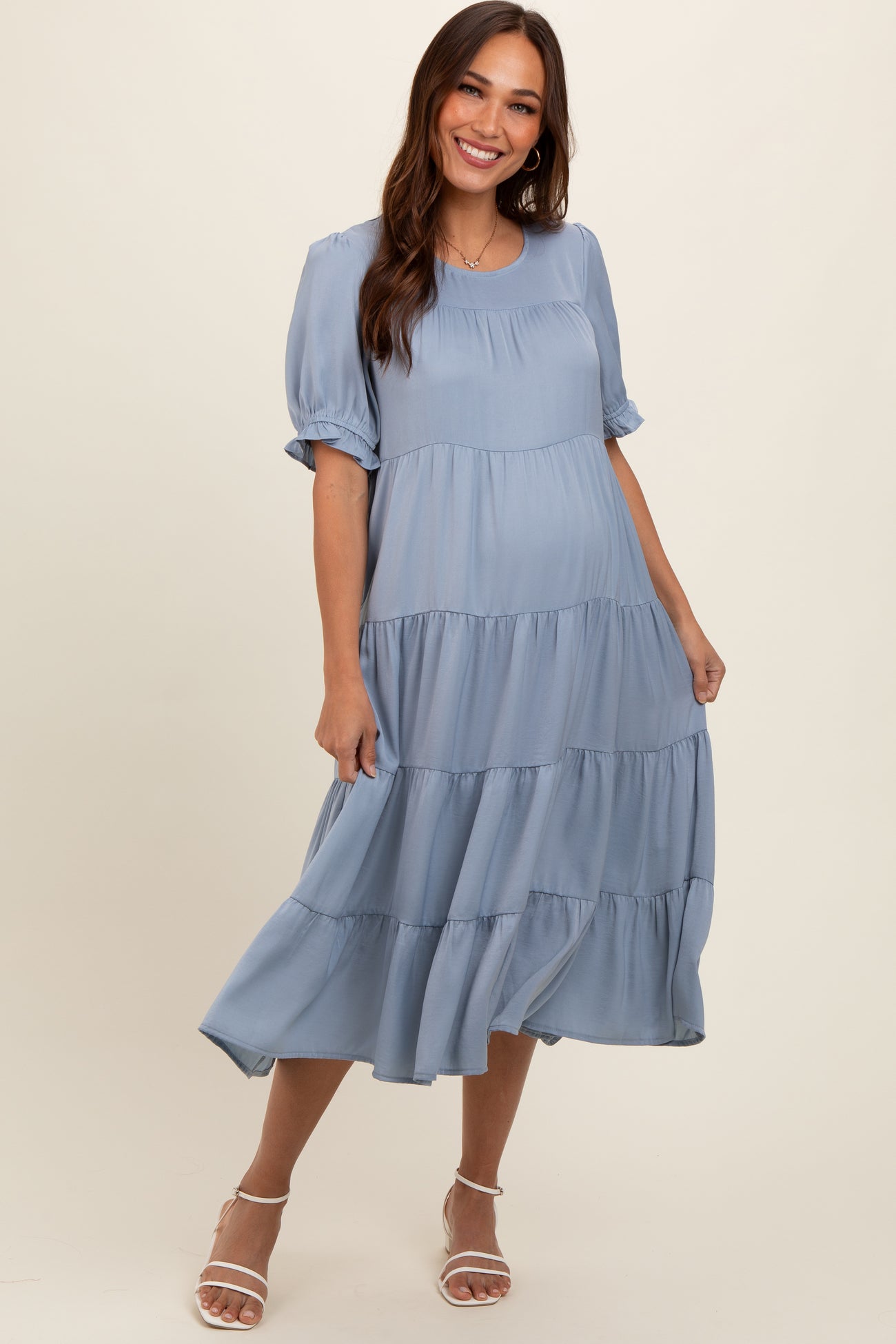 woman wearing a light blue tiered maternity dress with short puff sleeves and a flowing skirt, baby bump visible
