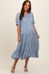 woman wearing a light blue tiered maternity dress with short puff sleeves and a flowing skirt, baby bump visible