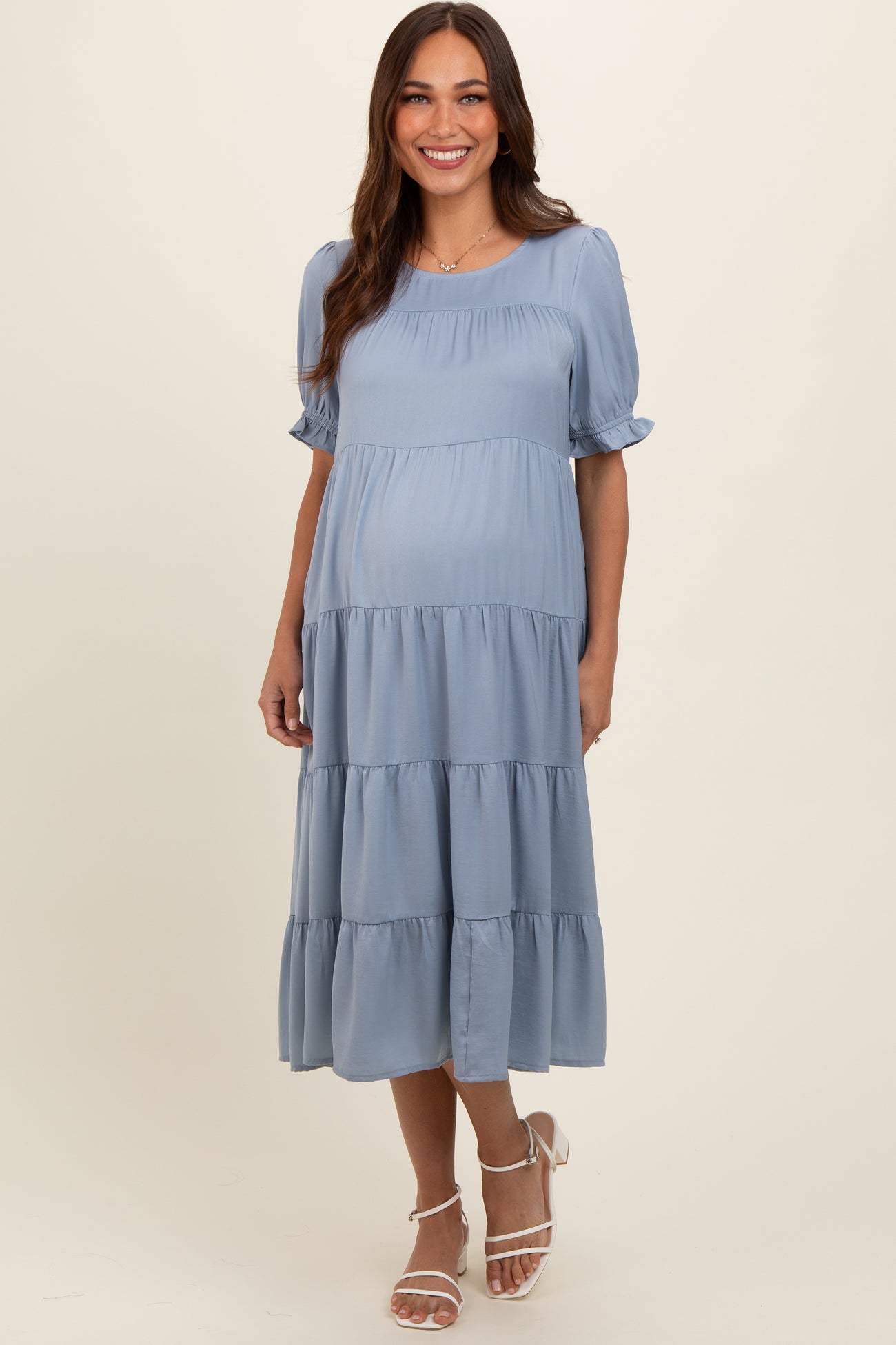 woman wearing a light blue maternity tiered midi dress with short puff sleeves and a baby bump visible