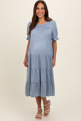 woman wearing a light blue maternity tiered midi dress with short puff sleeves and a baby bump visible