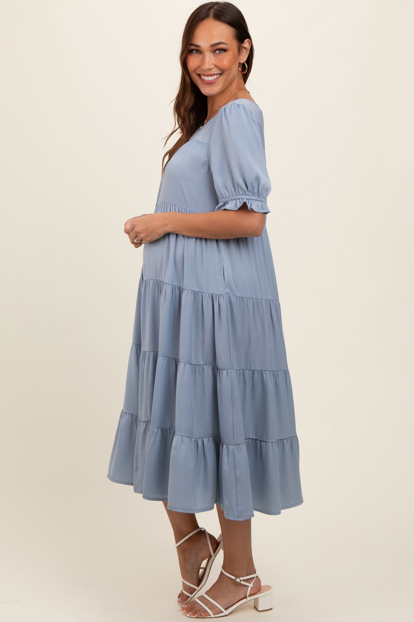 woman wearing a light blue tiered maternity dress with puff sleeves and a visible baby bump