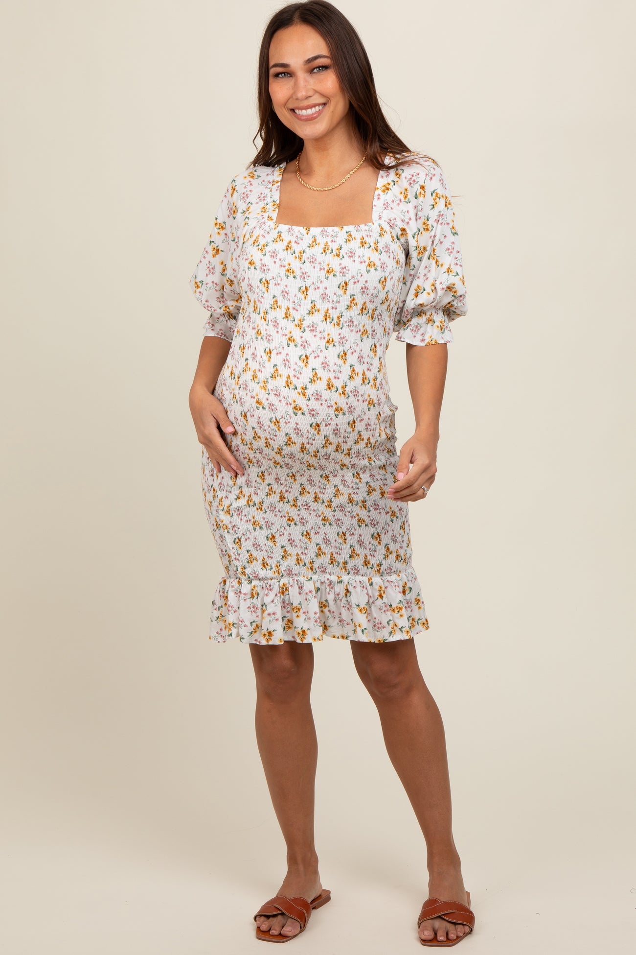 woman wearing a white maternity dress with floral print and puff sleeves, showing her baby bump