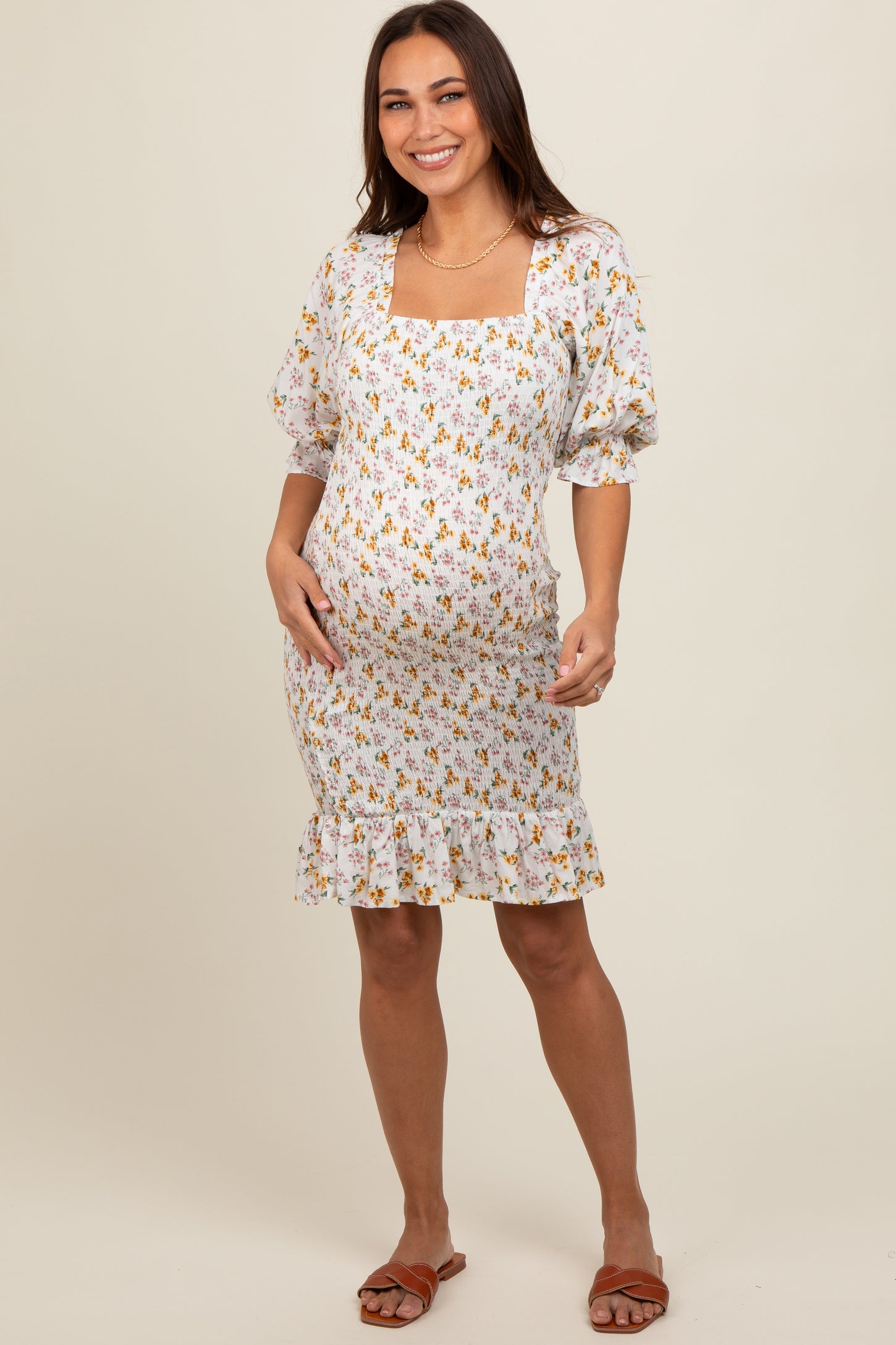 woman wearing a white maternity dress with floral print and puff sleeves, showing her baby bump