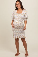 woman wearing a white maternity dress with floral print and puff sleeves, showing her baby bump