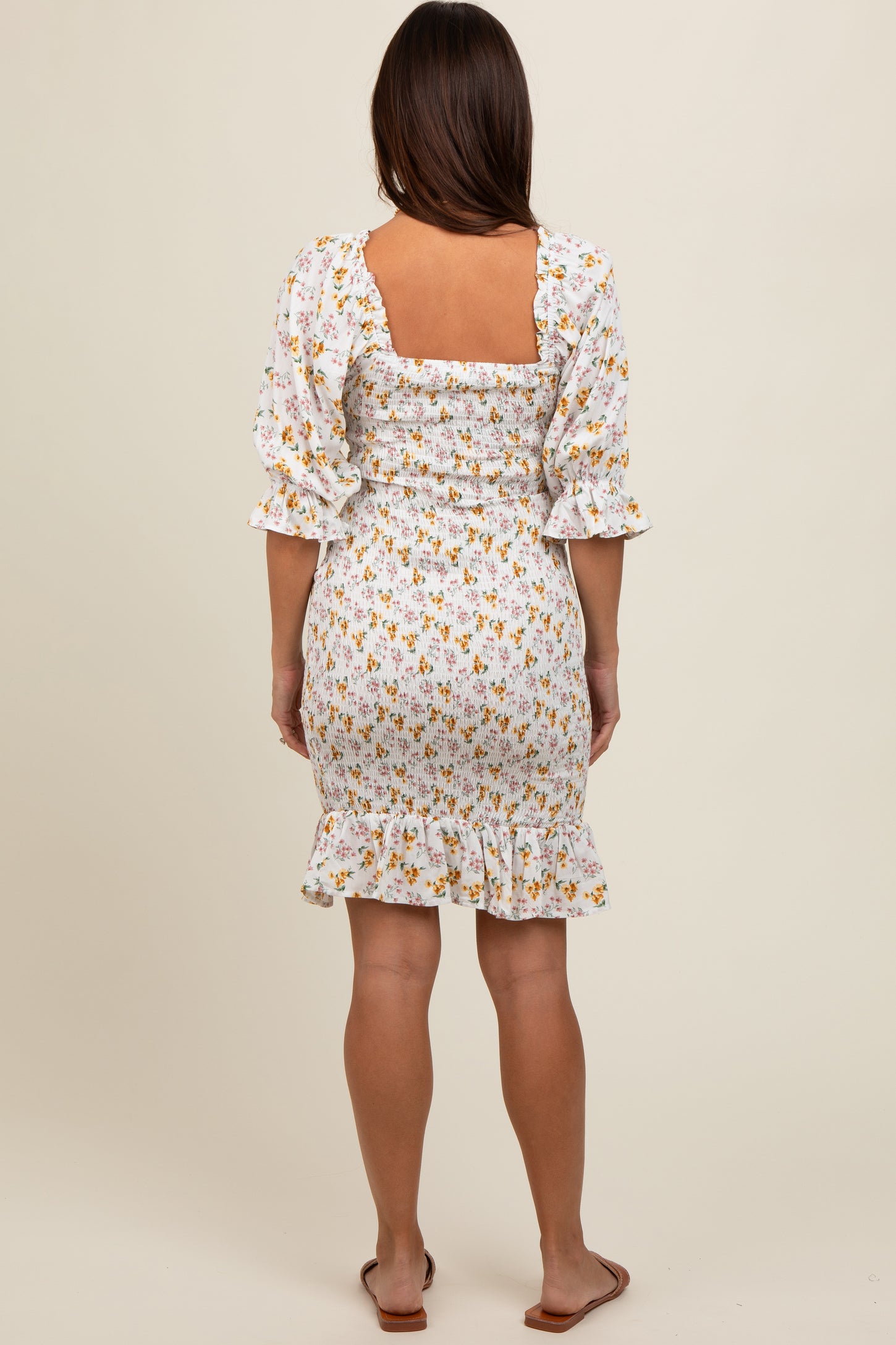 woman wearing a floral print maternity dress with puff sleeves and a fitted bodice, showing a baby bump from the back