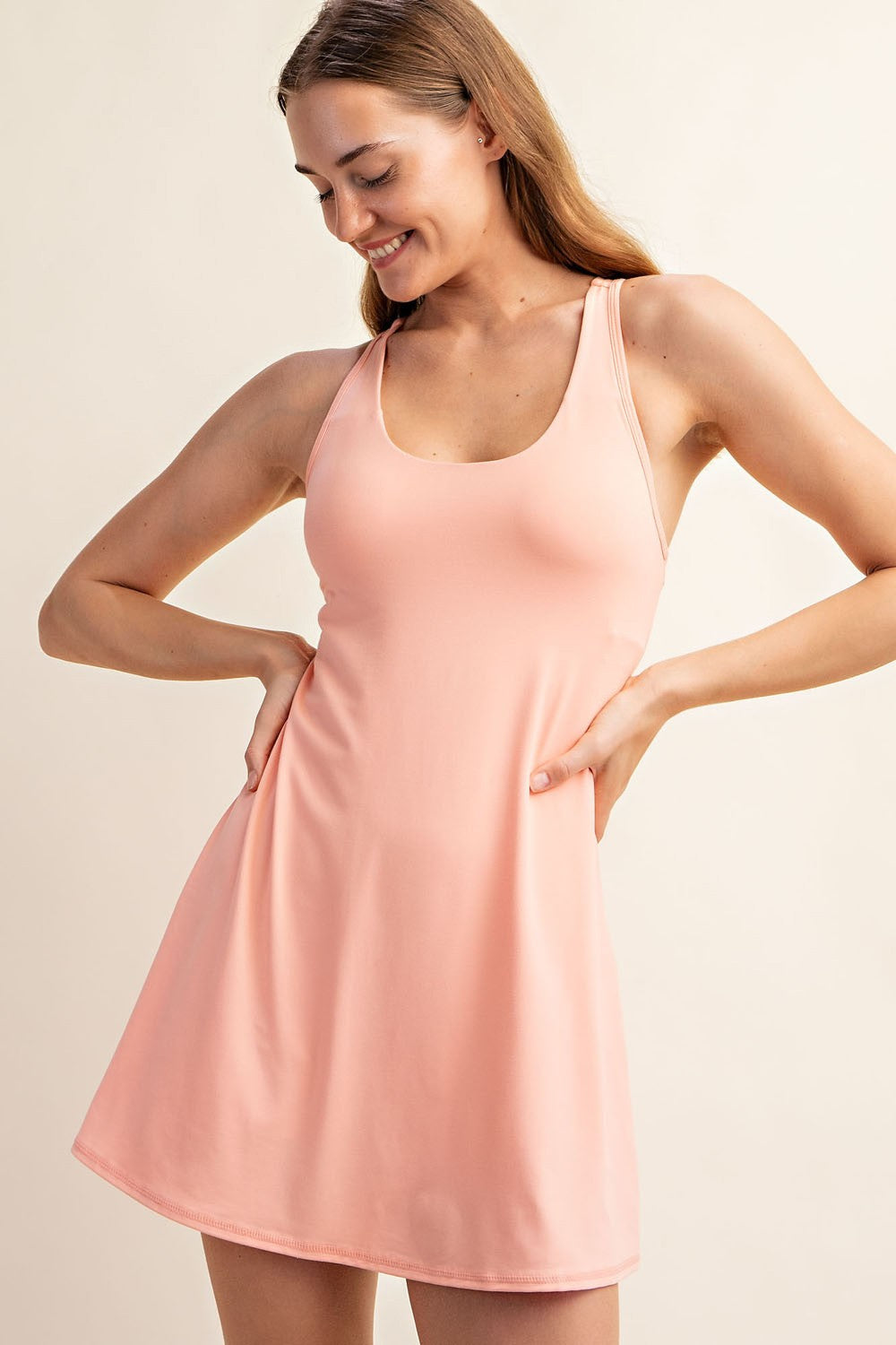 woman wearing a pink athletic tank dress with a fitted bodice and flared skirt