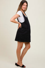 woman wearing a black denim maternity dress with a front pocket and a white t-shirt underneath, showcasing a baby bump