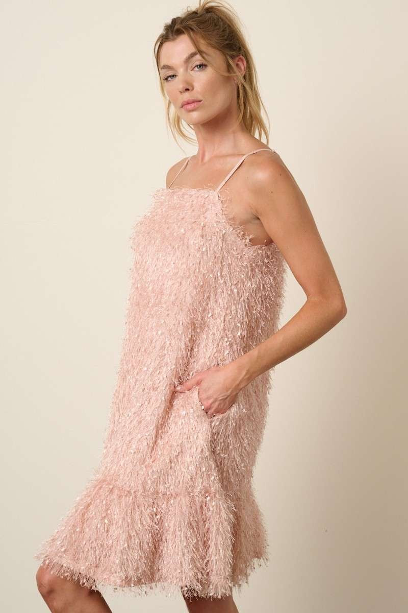 woman wearing a light pink fluffy textured dress with adjustable straps and side pockets