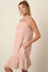 woman wearing a light pink fluffy textured dress with adjustable straps and side pockets