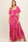 woman wearing a pink floral maternity maxi dress with puff sleeves and a tie waist, showcasing her baby bump